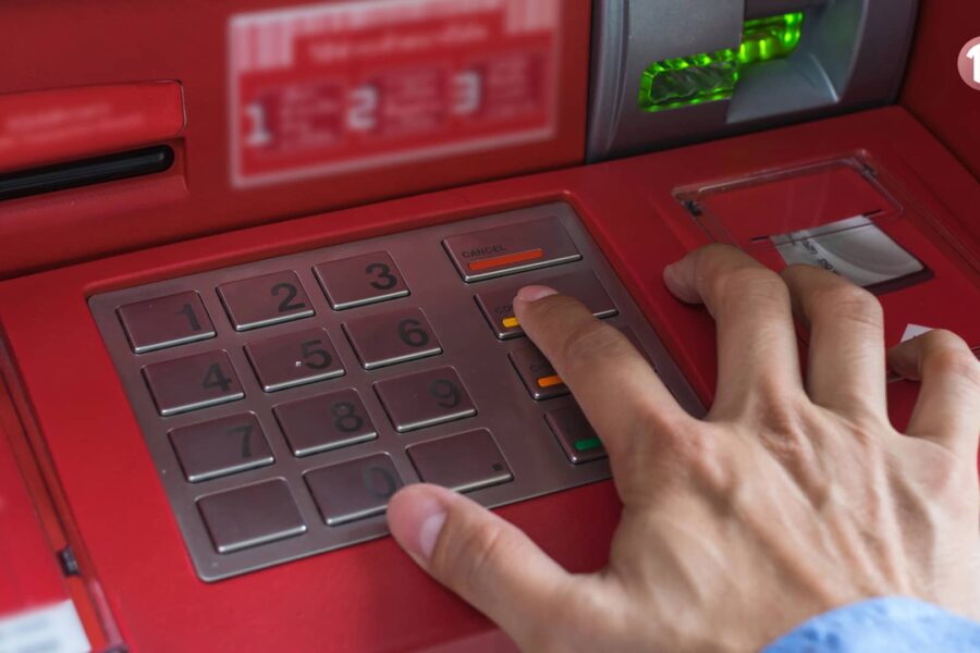 Mano presionando el botón "Cancelar" en un cajero automático rojo, ilustrando su función y precauciones de seguridad.